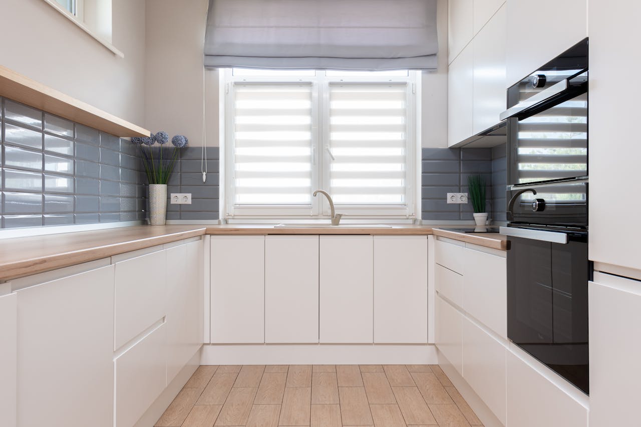 Interior design of modern kitchen in minimal style and furniture with smooth surface and windows with jalousie